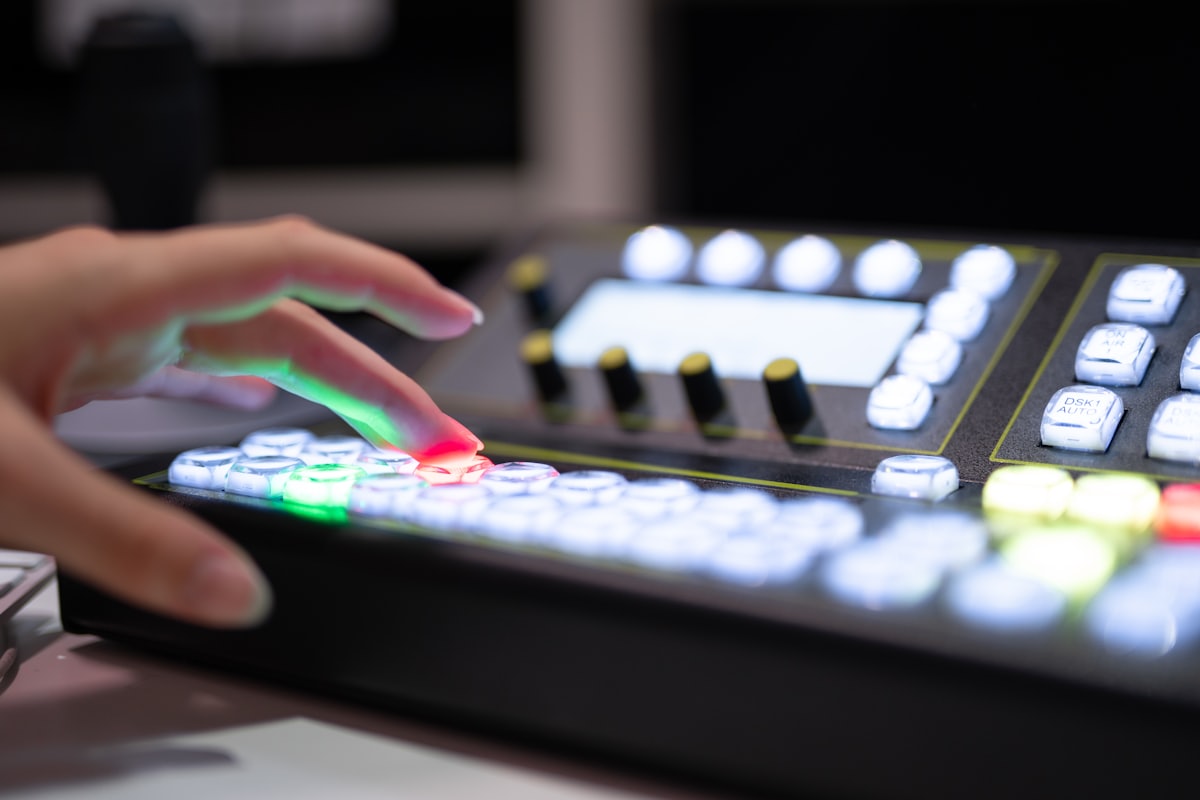 Hand on a vision mixer panel with illuminated source buttons