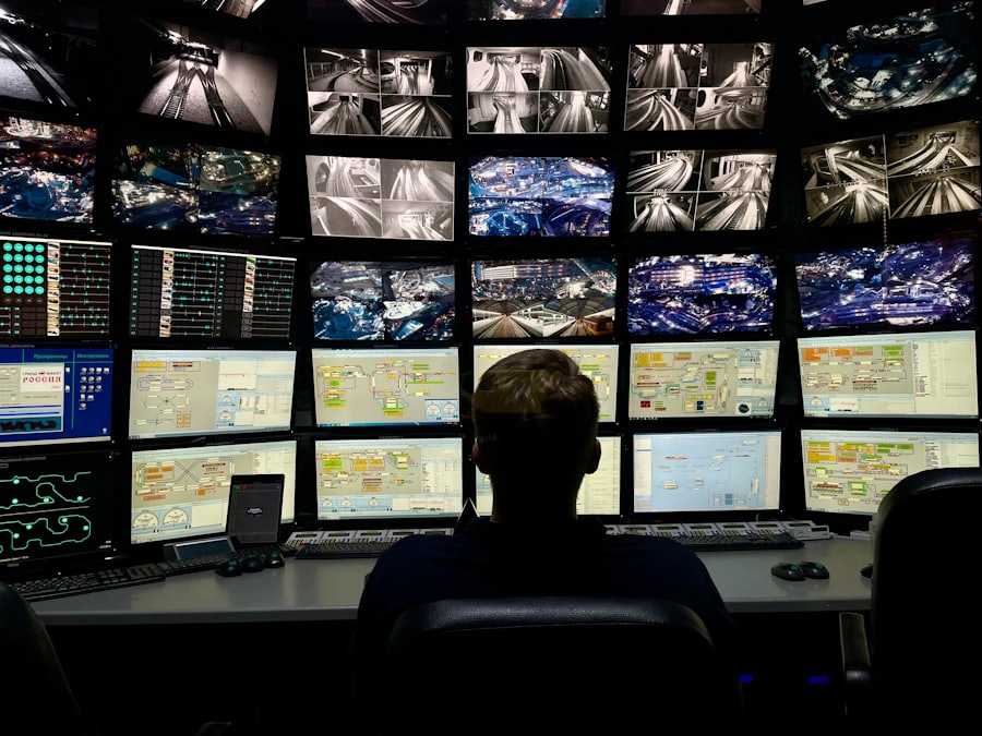 Operator at a control desk facing a wall of monitors
